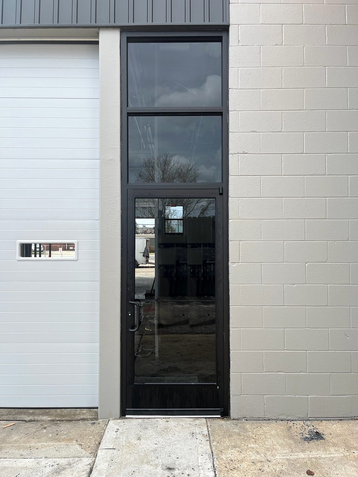 Black aluminum commercial storefront door with full glass and intermediate transoms above in Selma, AL