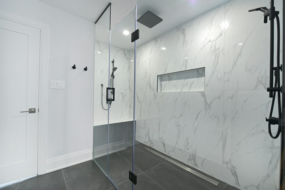 Modern bathroom with a frameless glass shower enclosure and marble walls